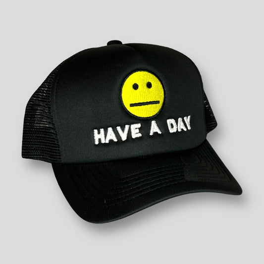 Black trucker cap with a yellow "no emotion" emoji face and white embroidered "have a day" writing underneath. This is a Mesh snapback. 